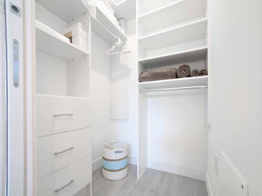 A white closet with open shelves, a hanging rod, and a basket.