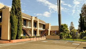 Ein Motel mit großer Schautafel, Parkplatz und einem Gebäude mit mehreren Balkonen und Treppen.
