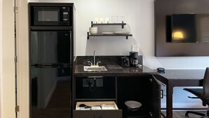 Eine kompakte Küchenzeile mit Mikrowelle, Kaffeemaschine und kleinem Spülbecken.