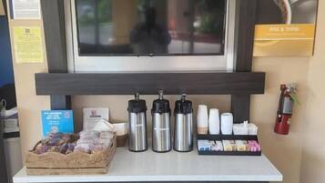 A reception desk with a flat-screen TV, a coffee station, and a basket of snacks.