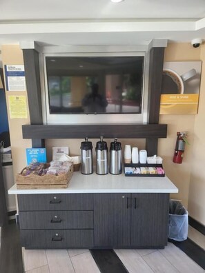 A reception desk with a flat-screen TV, a coffee station, and a basket of snacks. - Studio 6 Vallejo, Ca – Napa Valley (Vallejo)