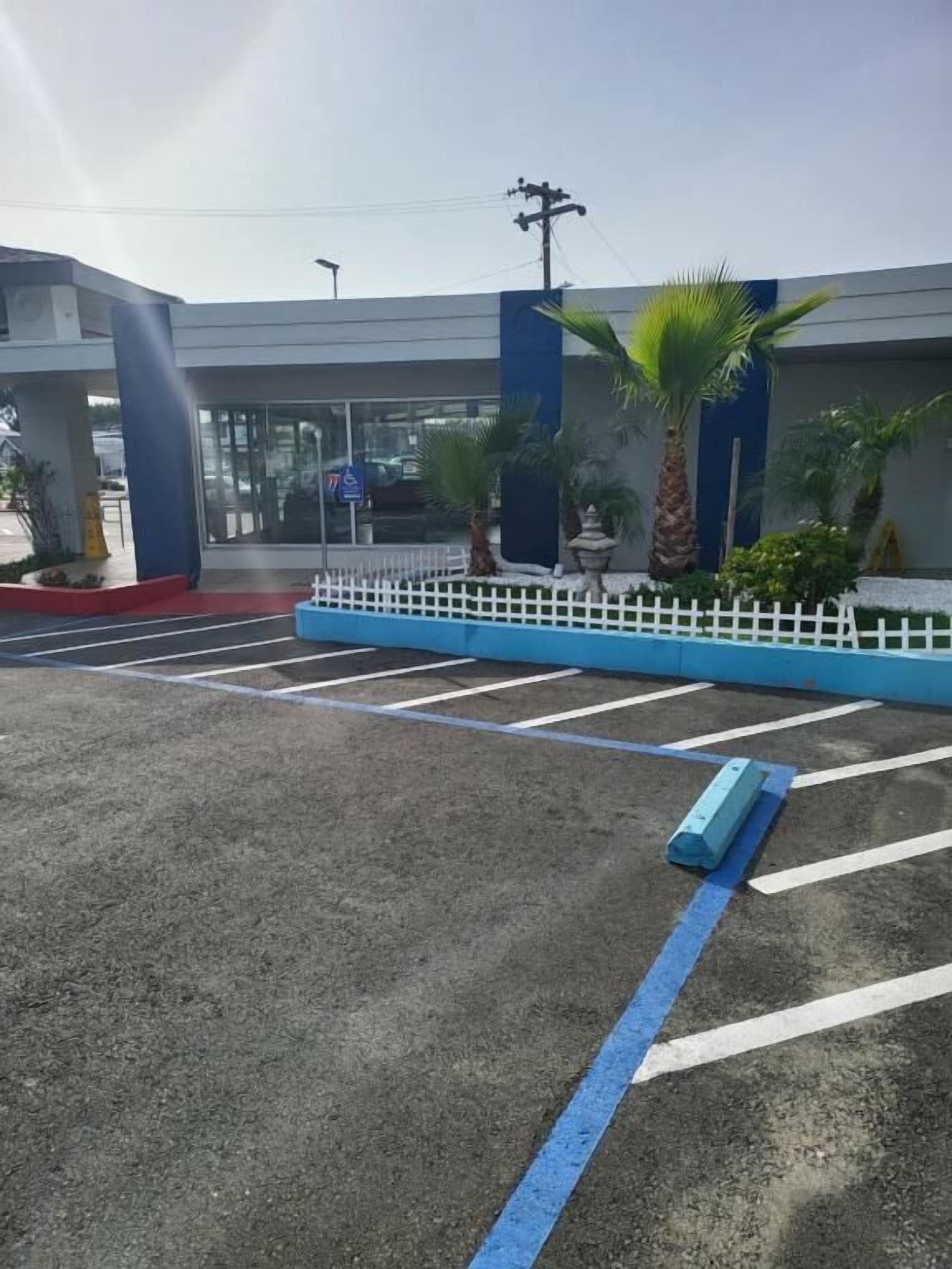 Estacionamento com vagas demarcadas e cerca branca.