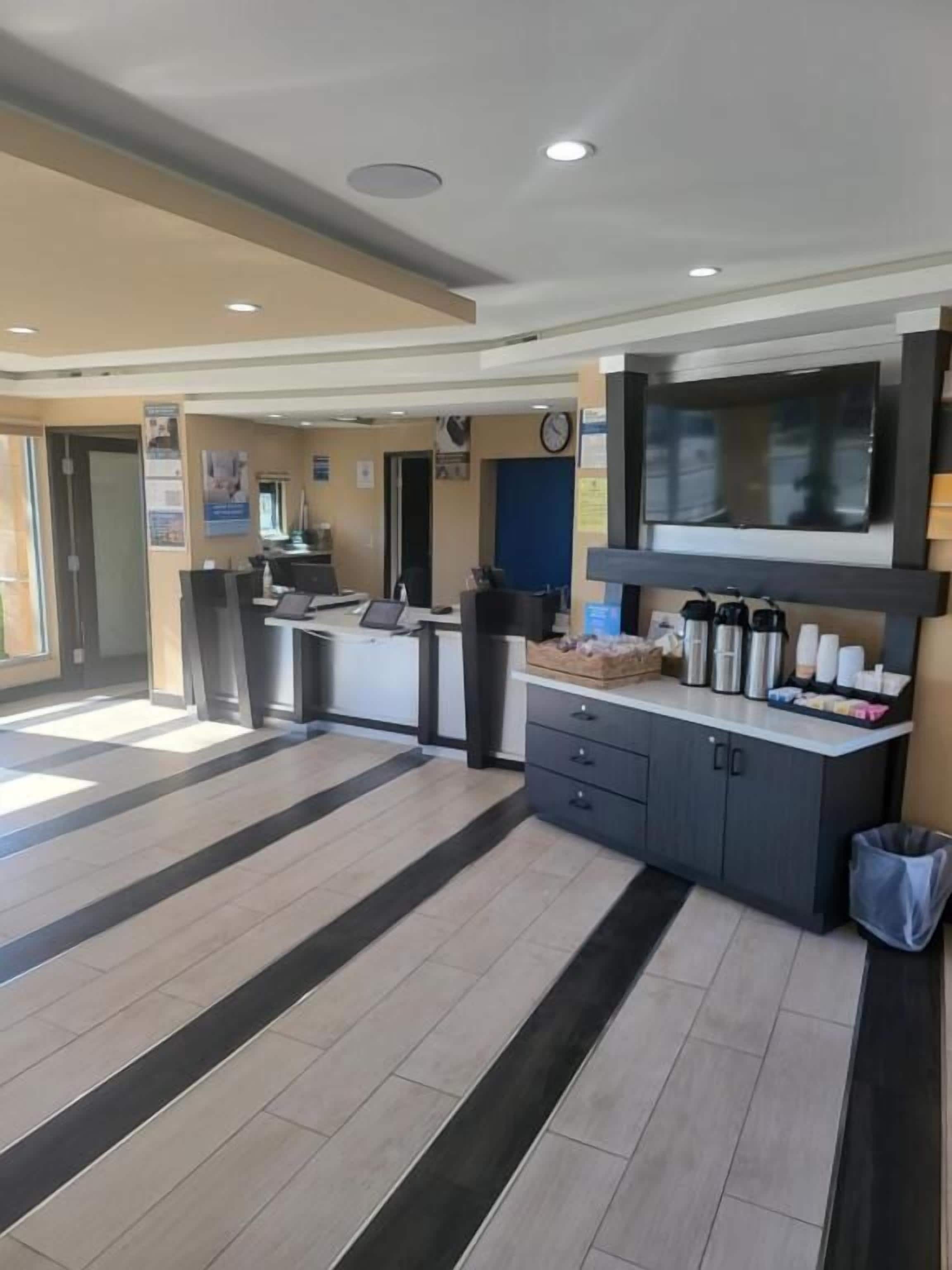 A modern hotel lobby with a reception desk, a trash bin, and a clock on the wall.