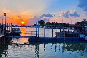 Ein Yachthafen mit vertäuten Booten, einer Brücke und einem Sonnenuntergang über dem Wasser.