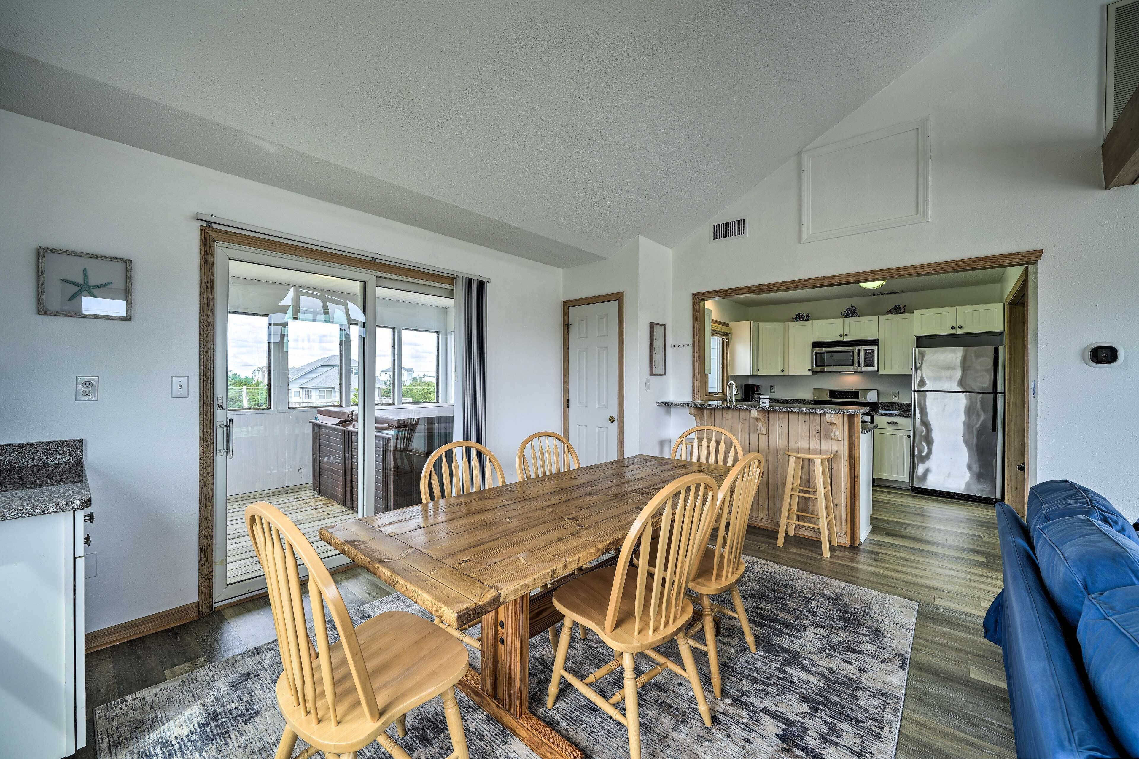 A modern kitchen with a central island, a dining area with a wooden table and chairs, and a living room with a blue sofa.