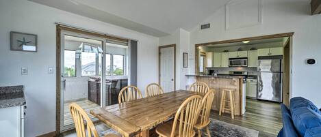 A modern kitchen with a central island, a dining area with a wooden table and chairs, and a living room with a blue sofa.