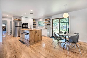 A modern kitchen with a central island, stainless steel appliances, and a dining area with a round table and chairs. - < 3 Mi to Pearl St: Home w/ Large Yard in Boulder (Boulder)