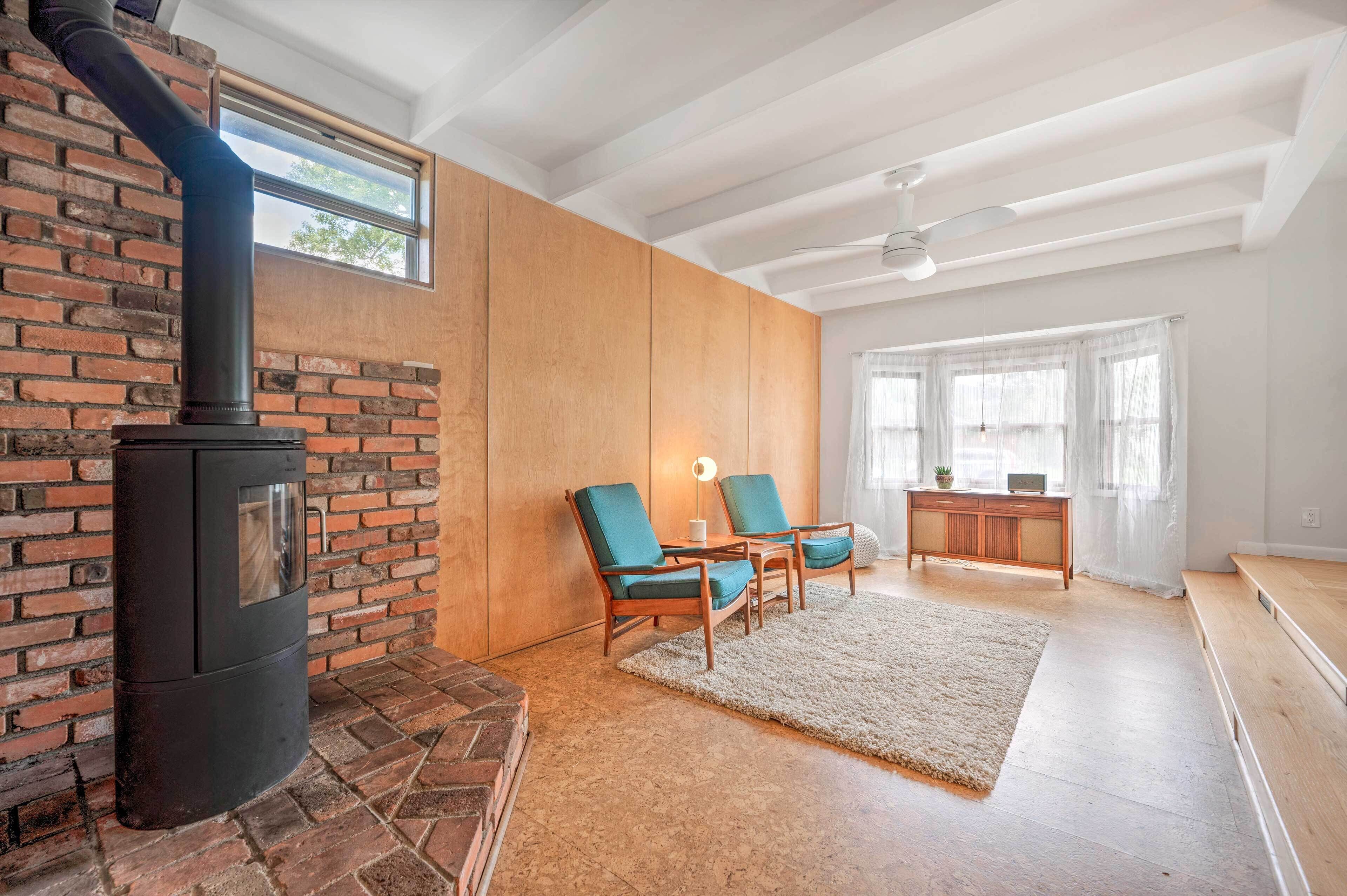 Een gezellige woonkamer met een open haard van baksteen, houten lambrisering en een groot raam.