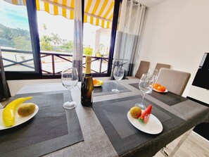 Een eettafel gedekt met wijnglazen, een fles wijn en borden met fruit.