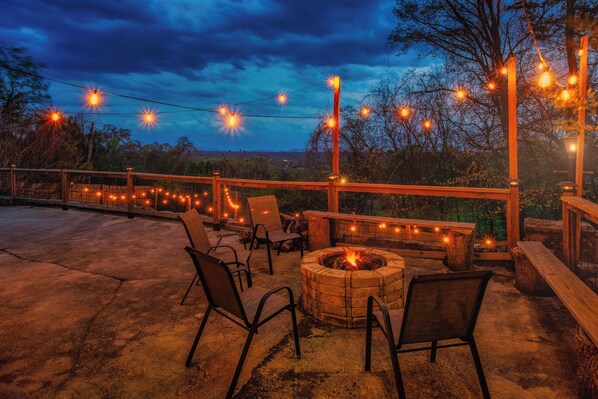 Relax by the fire pit in a serene outdoor setting surrounded by comfortable seating and a distant view.