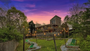 Una casa con patio trasero que incluye hoyos de mini golf y una terraza de madera.