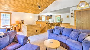 Acogedor interior de cabaña con techo de madera, comedor, cocina y sala de estar con dos sofás y una pequeña mesa redonda.