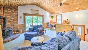 Una sala de estar acogedora con chimenea, sofás azules, un comedor y vistas al exterior.