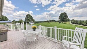 Eine Terrasse mit weißem Zaun, Grill und Gartenmöbeln.