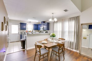 Una cocina moderna con armarios azules, una mesa de comedor de madera y una araña.