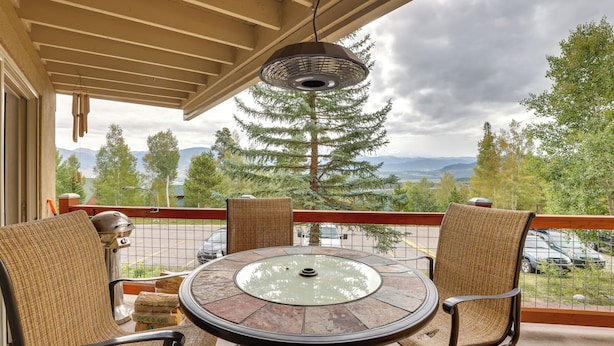 A balcony with wicker chairs, a glass-top table, and a hanging light fixture. - Silverthorne Condo w/ Lake Views: 10 Mi to Skiing! (Silverthorne)