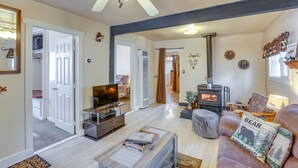 Een woonkamer met een open haard, televisie en een bank met decoratieve kussens.