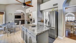 Una cocina moderna con encimeras de granito, electrodomésticos de acero inoxidable y un ventilador de techo.