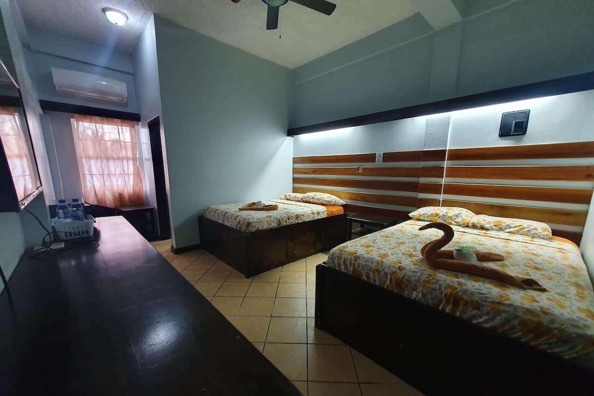 A hotel room with two beds, a desk, and a chair.