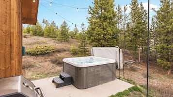 A hot tub and grill area with a view of a forested hillside.