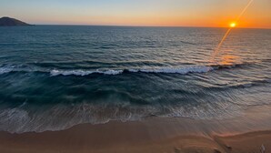 A beach with waves and a sunset.