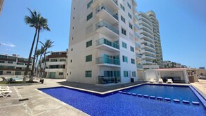 A modern hotel with a pool area, including lounge chairs and a small pool.