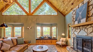 A cozy living room with a stone fireplace, wooden beams, and large windows. - STUNNING Mountain VIEW Lodge for 14! (Murphy)