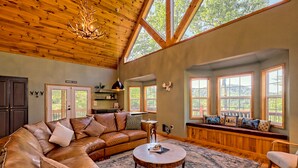 A spacious living room with a large leather sectional sofa, a round coffee table, and a built-in bench with cushions. - STUNNING Mountain VIEW Lodge for 14! (Murphy)