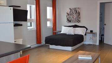 A modern bedroom with a bed, a TV mounted on the wall, and a zebra artwork.