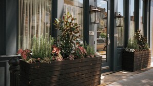 A building with large windows, wooden planters with plants, and a sign indicating "Rooms 15". - The Woodward Hotel (Macon)