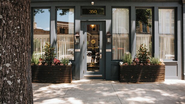 A building with a number '350' above the entrance, a door, and two planters with plants. - The Woodward Hotel (Macon)