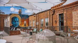 An outdoor patio with brick walls, metal chairs, and tables. - The Woodward Hotel (Macon)