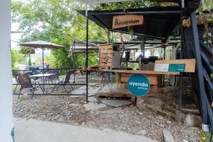 Zona exterior con mesas y sillas, un mostrador de recepción y un cartel que dice 'ayenda HOTELES'.