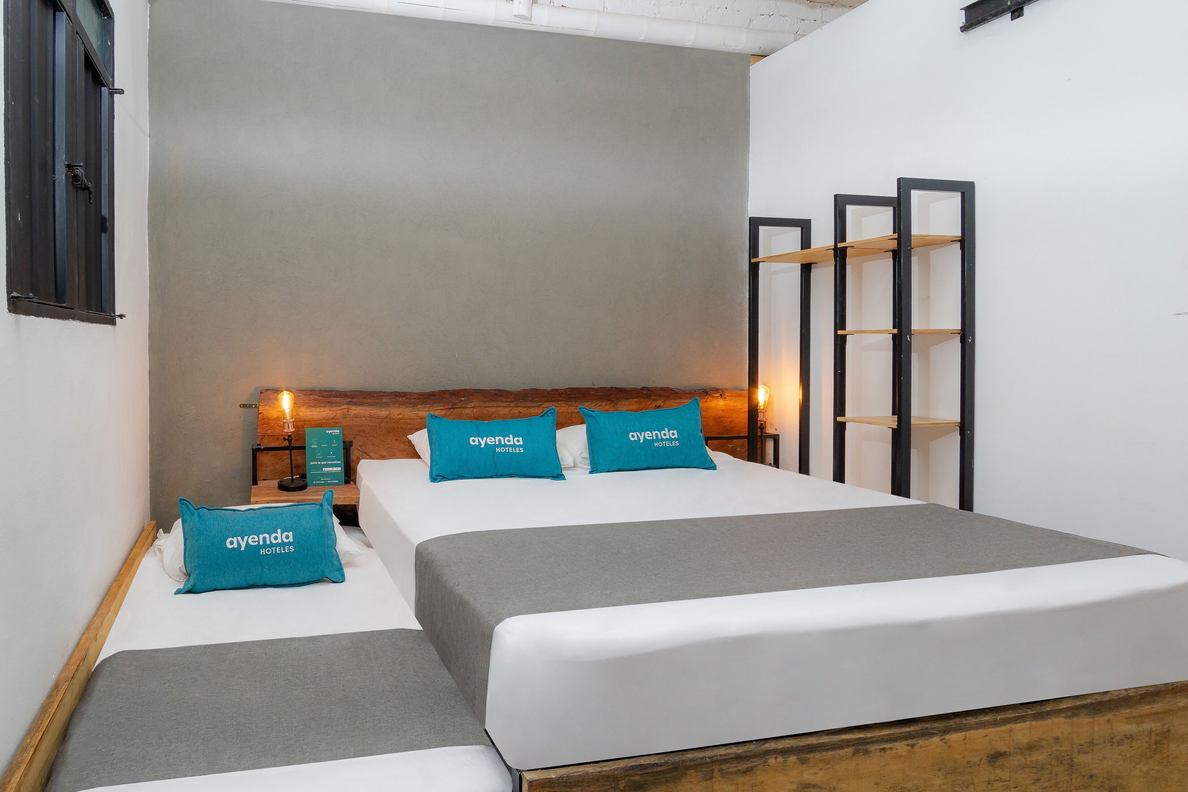 A hotel room with two beds, a wooden headboard, and a nightstand with a lamp.