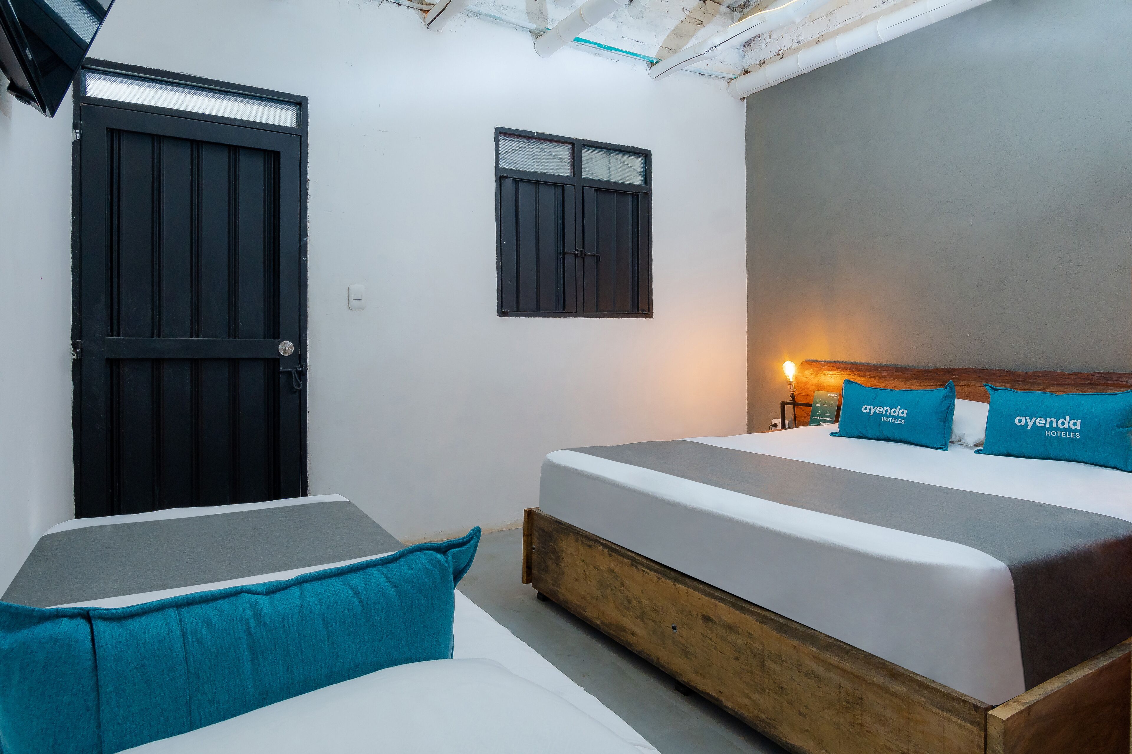 A bedroom with a large bed, a smaller bed, and a wardrobe. There is a window and a door.