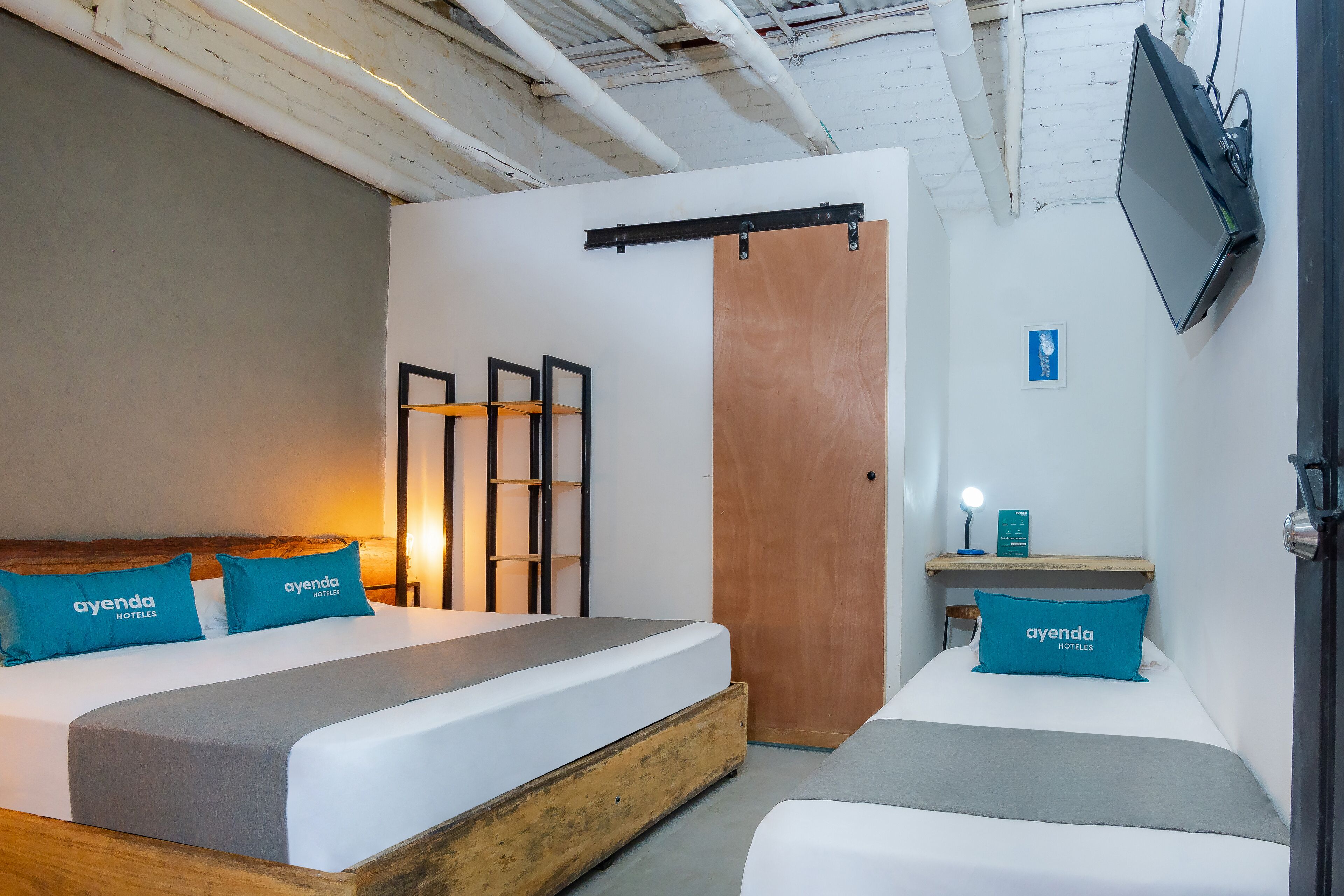 A modern hotel room with a bed, a desk, and a TV.