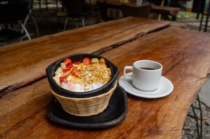 A bowl of yogurt topped with fruits and granola on a wooden table.
