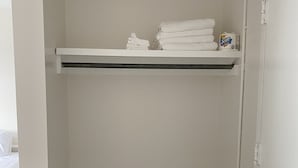 A small, white closet with a wooden floor, containing neatly folded white towels and a box of Scott detergent. - Stylish 1 Bedroom Apartment in Gadsden, AL (Gadsden)