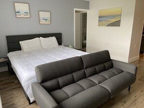 Relax in this serene bedroom with a large bed, a comfortable bench, and beautiful beach-inspired artwork.
