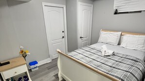 Un dormitorio con cama, mesita de noche, cómoda y ventana con persianas.