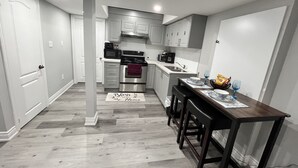 Una cocina moderna con gabinetes blancos, electrodomésticos de acero inoxidable y una mesa de comedor de madera con taburetes de bar.