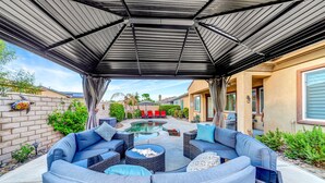 A covered outdoor seating area with a pool, wicker furniture, and a brick wall.