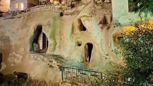 A cave-like structure with a stone staircase leading up to a small building with a cross on top. - Ela cave house (Ürgüp)