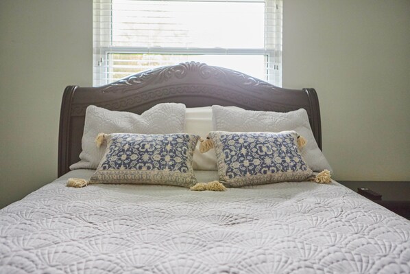 Un lit bien fait, avec une couvre-lit à motifs et deux coussins décoratifs.