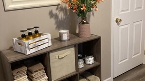 A wooden console table with storage drawers, a vase of flowers, and toiletries.