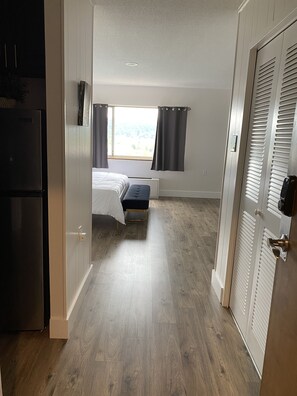 A compact room with a bed, a small table, and a window with curtains. - Sophisticated Studio Apartment in Gadsden, AL (Gadsden)