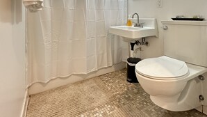 A bathroom with a toilet, sink, and shower curtain. - Sophisticated Studio Apartment in Gadsden, AL (Gadsden)