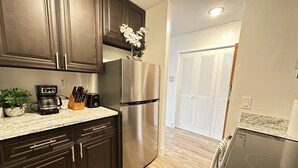 A modern kitchen with dark wooden cabinets, a stainless steel refrigerator, a coffee maker, and a toaster. - Sophisticated Studio Apartment in Gadsden, AL (Gadsden)