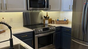 A modern kitchen with white cabinets, stainless steel appliances, and a marble countertop. - Upscale condo centrally located in Baton Rouge!! (Baton Rouge)