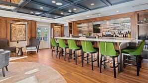 A modern bar area with a wooden ceiling, green bar stools, and a bar counter.